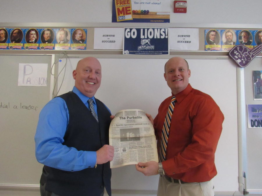 Assistant Principal John Saras and social studies teacher Doug Graff show off a copy of the paper from their era.