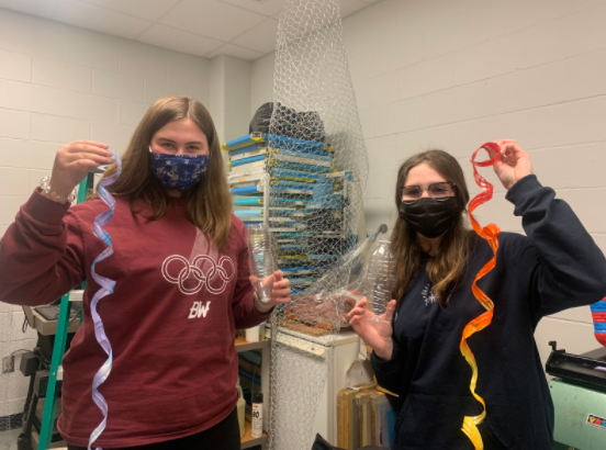 Junior Jenna Fox (left) and junior Jordan Gremba show off how the National Art Honor Society is turning plastic water bottles into art for a new installation.