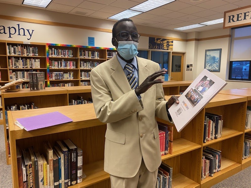 Gabriel Ajang, who at age 9 became one of the Lost Boys of Sudan, shows the childrens book he has written. Ajang spoke to Honors English 9 students after they read a magazine article about the Lost Boys.