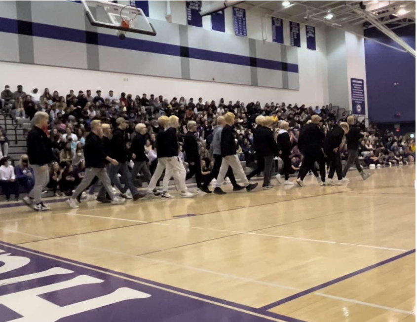 Hockey players, with their hair newly dyed blond for the playoffs, walk across the gym during the pep rally.