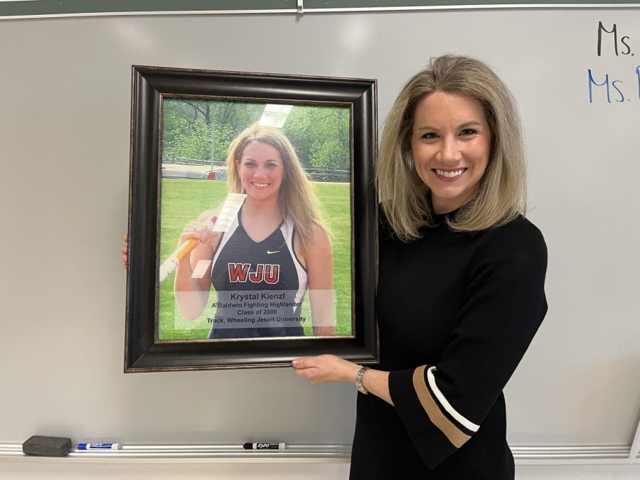 Krystal Schulte holds an image of her younger self in her Wheeling Jesuit University track uniform.