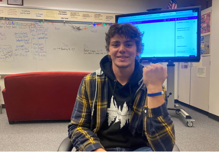 Senior Christian Forgacs shows off one of the bracelets that Spanish Club members are selling to help a family from El Salvador.