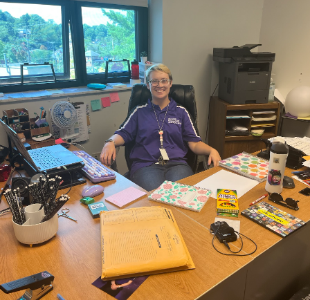 Music Teacher Emery Palmer sits at their desk. 