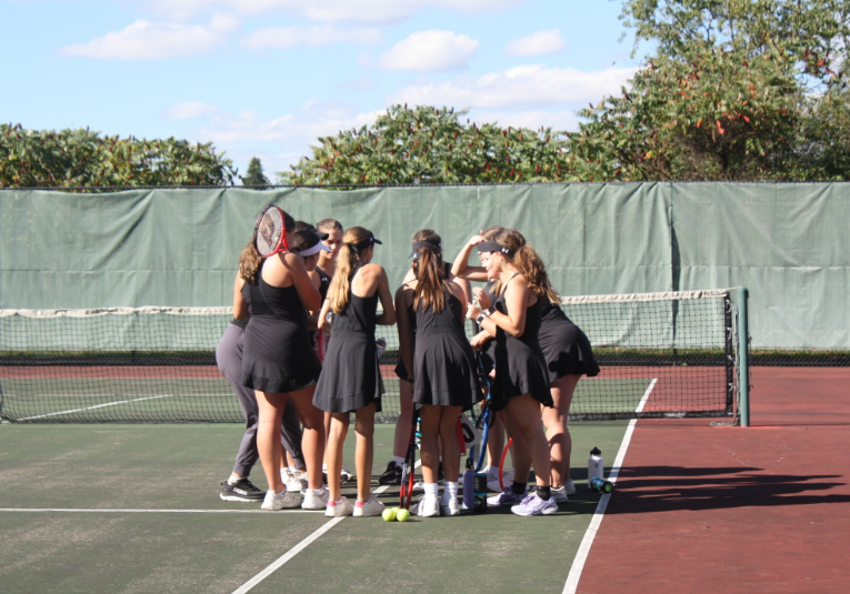 The girls varsity tennis team shares words of encouragement before their matches. 