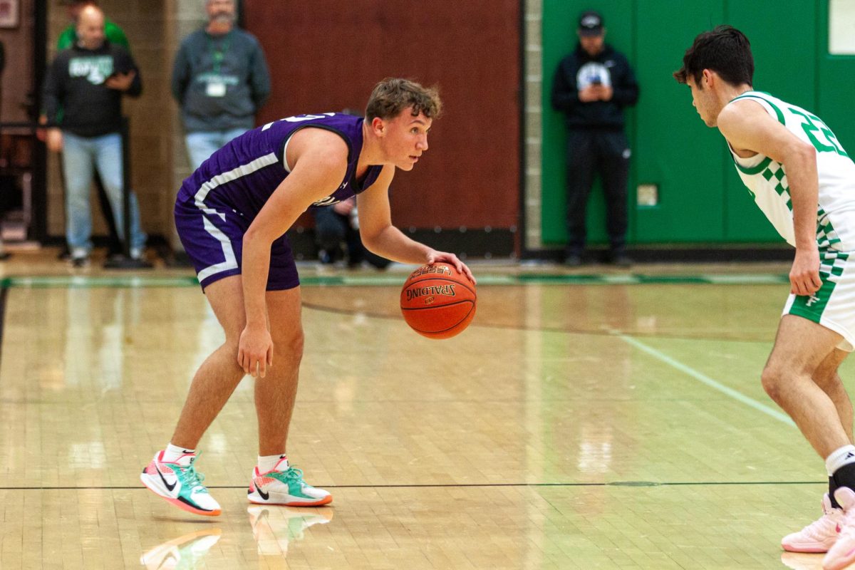 Junior Max Marzina dribbles the ball midcourt during the first quarter.