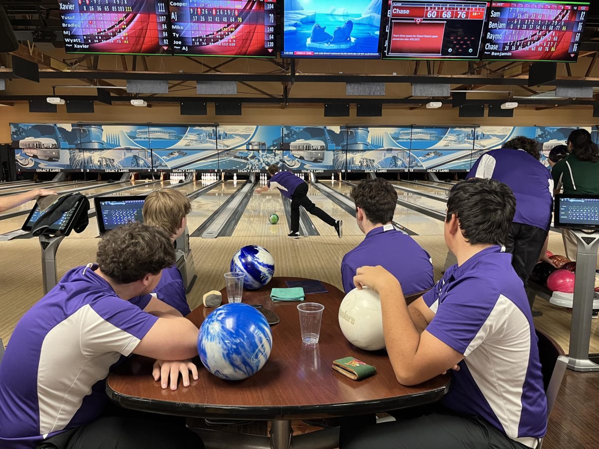 Members of the bowling team look on as junior AJ Amato bowls.