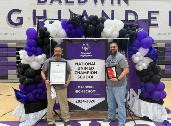 Timothy Laughlin and Eric Jankoski stand with the National Unified Champion School banner. 