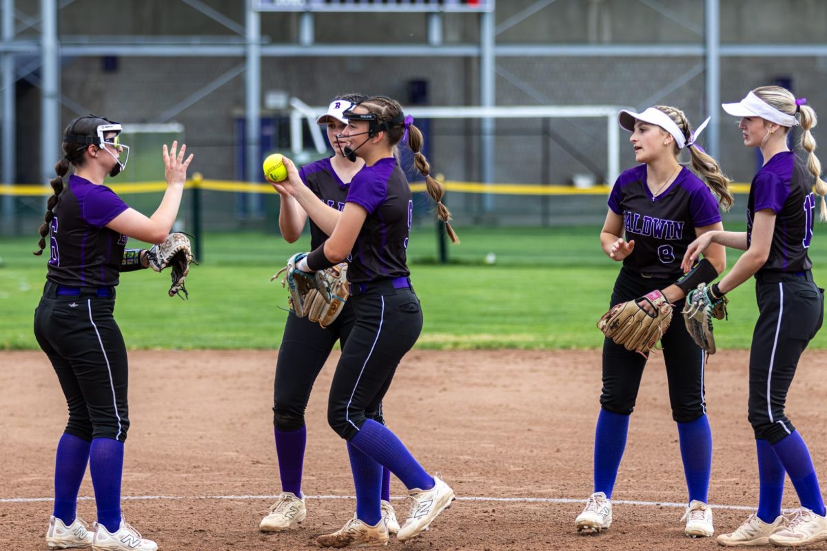The softball team talks before the game begins against Trinity.