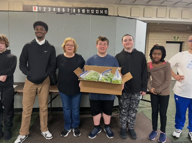 Jeremy Zivkovic (from left), Anton Dancy, Betty Niziol, Anzino Burg, Jonathan Madden, Avonni Dockery, and Dom Meloni hold the lettuce that is being donated to Meals on Wheels.