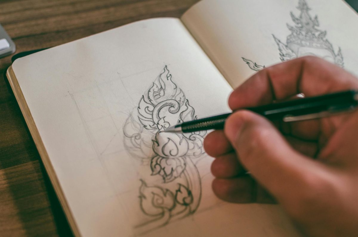 An artist draws on a sketchpad with a pencil. Image via Pexels by Pixabay. 