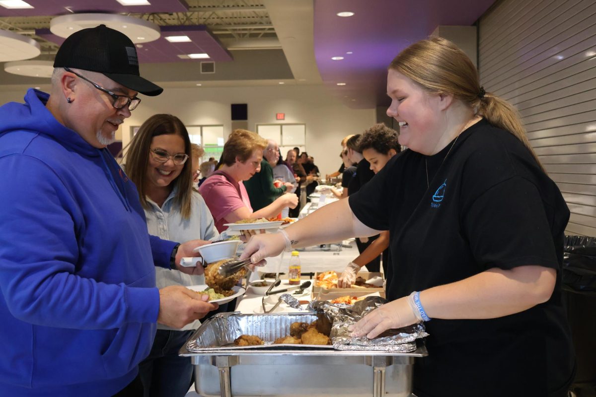 Senior Becca Wilds helps serve chicken to community members during the event. 